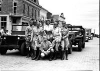 [Possibly Sally Rand sitting on jeep amidst military men]