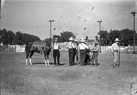 [Autry at microphone, four-member band behind and man in jodhpur pants holding champion]