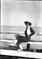 [Unidentified cowgirl sitting on fence]