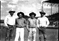 [Four unidentified cowboys standing in arena]