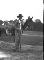 [Possibly Floyd Gale in hat, jacket and tie with Pinto horse wearing trick riding saddle]