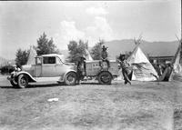 [Three Indian men in cowboy hats next to trailer attached to car]