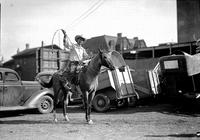 [Ike Rude posed on horse with rope in hand and horse trailers behind]