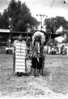 [Indian man in feathered headdress standing beside Indian woman]