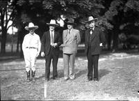 [Group of four western attired men including California Frank standing in line in front of trees]