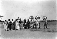 [Group of Indian men, women, and children in native dress in arena]