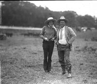 [Unidentified cowgirl and cowboy standing outdoors]