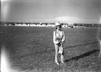 [Unidentified cowgirl in field holding boots]