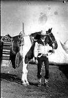[Cecil Cornish in two-toned shirt holding Pinto horse; Diamond shaped silver trim on bridle]