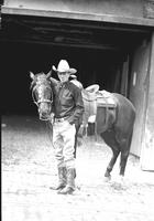 [Col. Jim Eskew stands with horse in front of barn entrance]