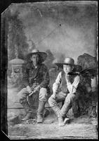 Two young cowboys with large hats, one whittling