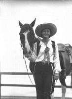 [Unidentified cowgirl posed beside horse]