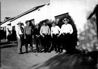 [Six unidentified cowboys standing in front of house]