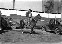 [Unidentified cowboy in jacket atop horse holding a rope loop to his side]