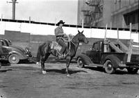[Unidentified cowboy in jacket atop horse holding a rope loop to his side]