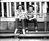 [Two unidentified women sitting on folding chairs in grandstand]