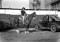 [Possibly Jack Sellers wearing jacket, holding rope, and mounted on horse]