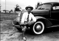 [Unidentified cowboy sitting on bumper of auto with Oklahoma '44 license]