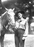 [Unidentified cowgirl standing by horse]