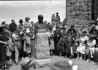 [Bust of Will Rogers in foreground at Shrine dedication with audience looking on]