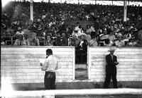 [Tim McCoy sits in center in black with "Guest" ribbon; women and men in box seats with him]