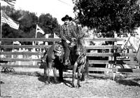 [Possibly Tommy Horner in striped shirt on horse with tooled two-tone saddle]