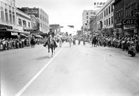 [Single unidentified cowboy leads parade down city street]
