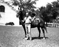 [Cowboy, hat in hand, holding Pinto horse; RJR on saddle]