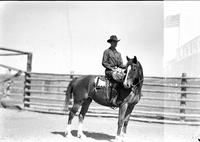 [Unidentified Cowboy on horseback holding coil of rope]