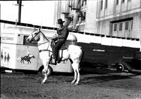 [Unidentified cowboy posed on horse in front of George Pitman trailer]