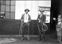 [Jake McClure & Allen Holder in street clothes holding their ropes while a boy in knickers looks on]