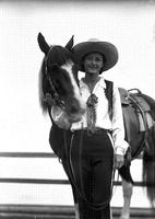 [Unidentified cowgirl posed beside horse]