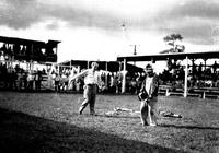 [Unidentified man using whip on or near unidentified rodeo clown]