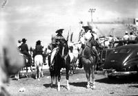 [Two men on horseback (One probably Autry on Champion) other riders and cars in background]