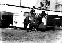[Unidentified cowboy posed on horse in front of George Pitman trailer]