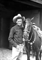 [Col. Jim Eskew and Black horse with silver mounted tack in front of large barn door]
