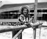 [Unidentified cowgirl leaning on fence]