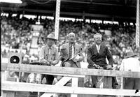 [Ray Talbot sitting behind fence with two unidentified business-suited men]