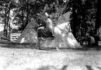 [Indian Woman on horseback in front of two tipis in picnic area]