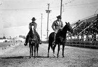 [Two unidentified Cowboys on horses in arena]