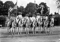 [Mamie Francis & California Frank on horses amid three mounted cowgirls and two mounted cowboys]