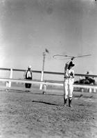 [Young unidentified cowboy spinning rope loop above his head]