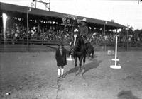 [Possibly Jack King on horse holding a large bouquet of flowers being led by a girl in a coat]