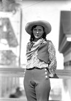 [Unidentified cowgirl posing by rail]