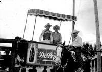 [Possibly Everett Colborn on horse standing in front of raised stand holding Gene Autry and another]