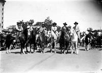 [Six unidentified cowboys on horses ready for parade]