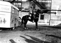 [Fred Beeson posed on horse near George Pitman trailer]