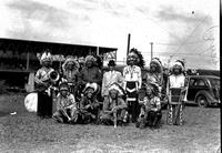 [Ten Indian marching band members with instruments and one man in business clothes near car]