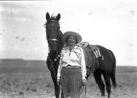 [Unidentified cowgirl standing by horse]