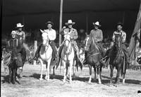 [Five unidentified cowboys on horseback and a clown on a donkey]